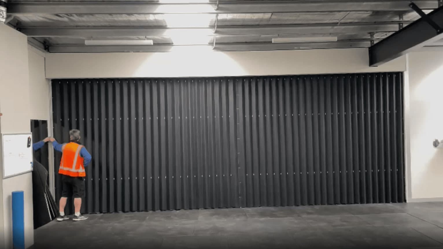A large vinyl accordion partition being drawn closed across a commercial opening