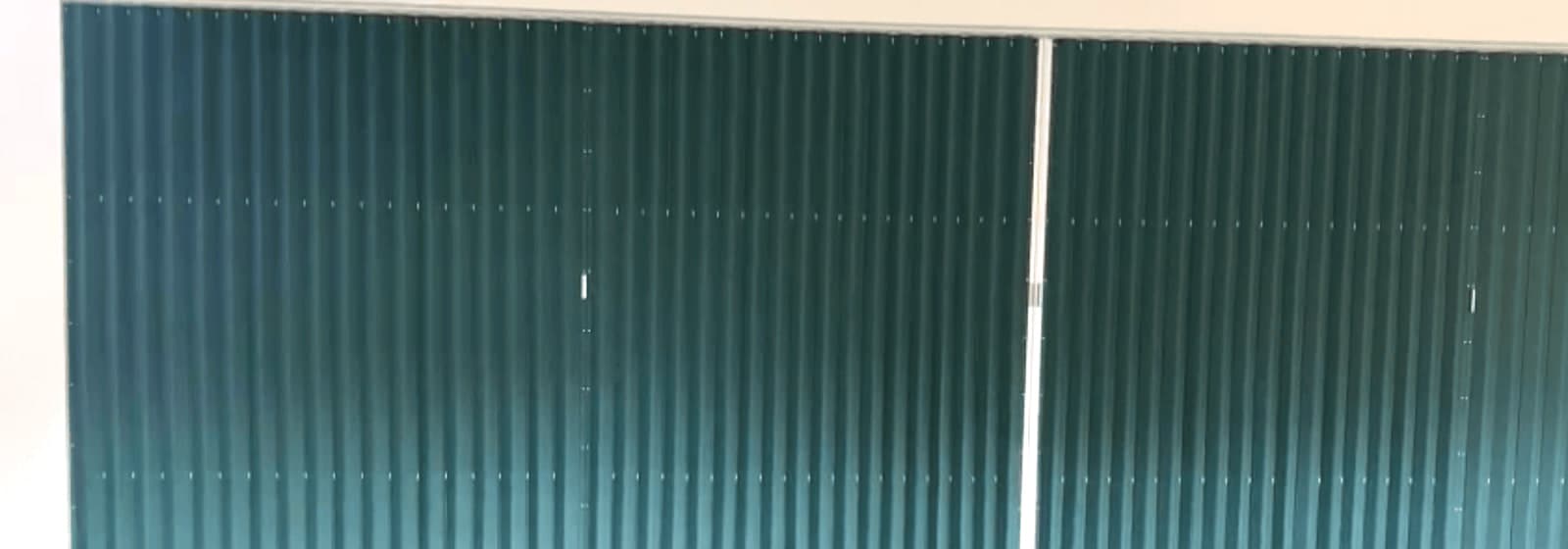 A vinyl accordion door closed across the full width of a hall