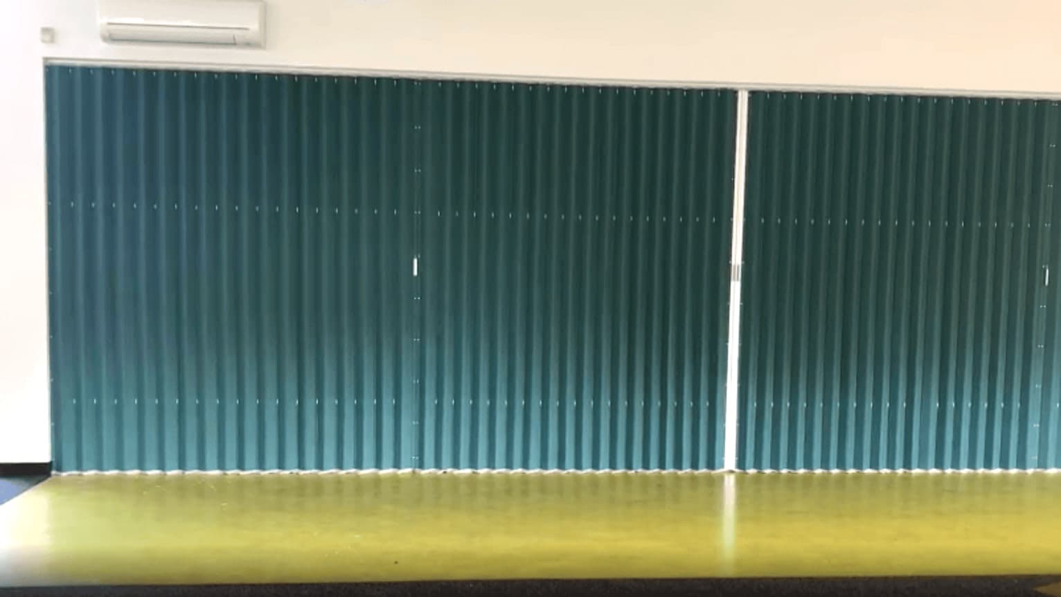 A vinyl accordion door closed across the full width of a hall